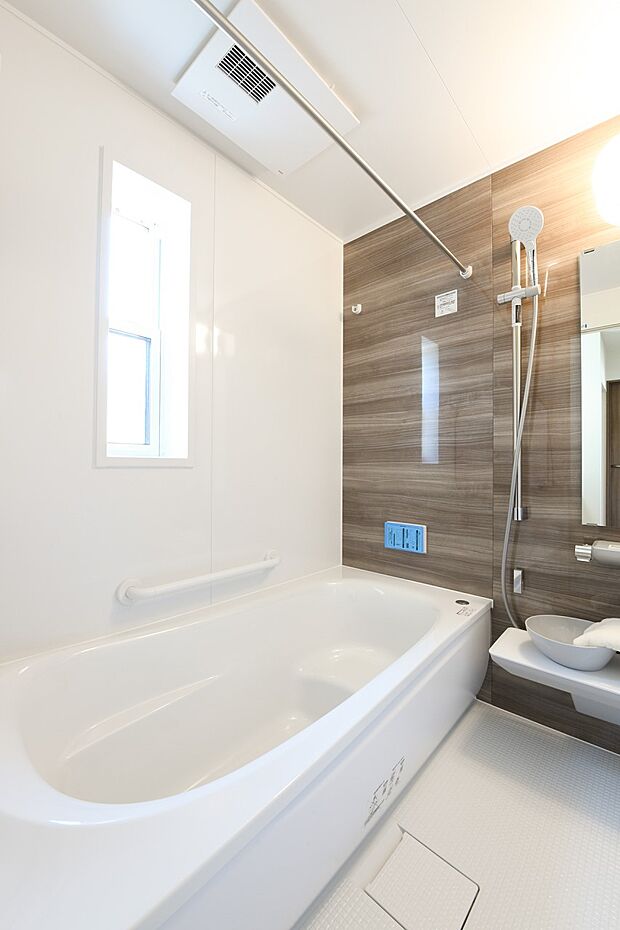 【浴室】木目調の壁面がアクセントになった、清潔感あるホワイトを基調とした空間。温かみが感じられ、ほっとできる色合いは、のんびりくつろぐ浴室にぴったりです。（1号棟）