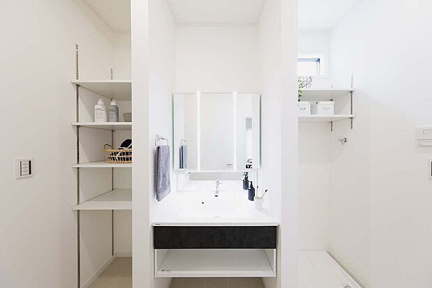 【5号地モデルハウス】玄関ホールからLDKへと通り抜けできる洗面室。ワイドな洗面台の左横には可動棚を備えた奥行きのあるリネン棚を設置。