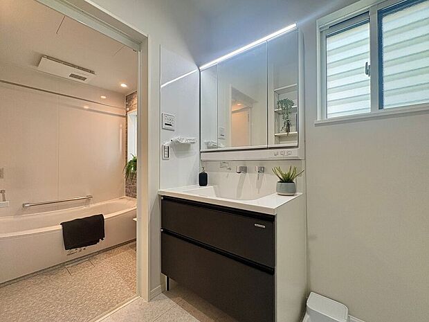 【洗面室】洗練されたデザインと清潔感のある空間で、タオルや化粧品を効率的に収納できます。3面鏡の鏡の裏には便利な収納が備わっており、毎日の身支度がスムーズに行えます。