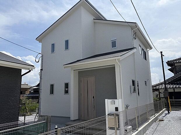 【A-2号棟 清潔感と上質感を兼ね備えたシンプルモダンな住まい】明るいホワイトの外観が街並みに映える一邸。玄関ポーチにはアクセントカラーを採用し、洗練されたデザイン性を演出しています。落ち着いた雰囲気と暮らしやすさを感じられる住まいです。