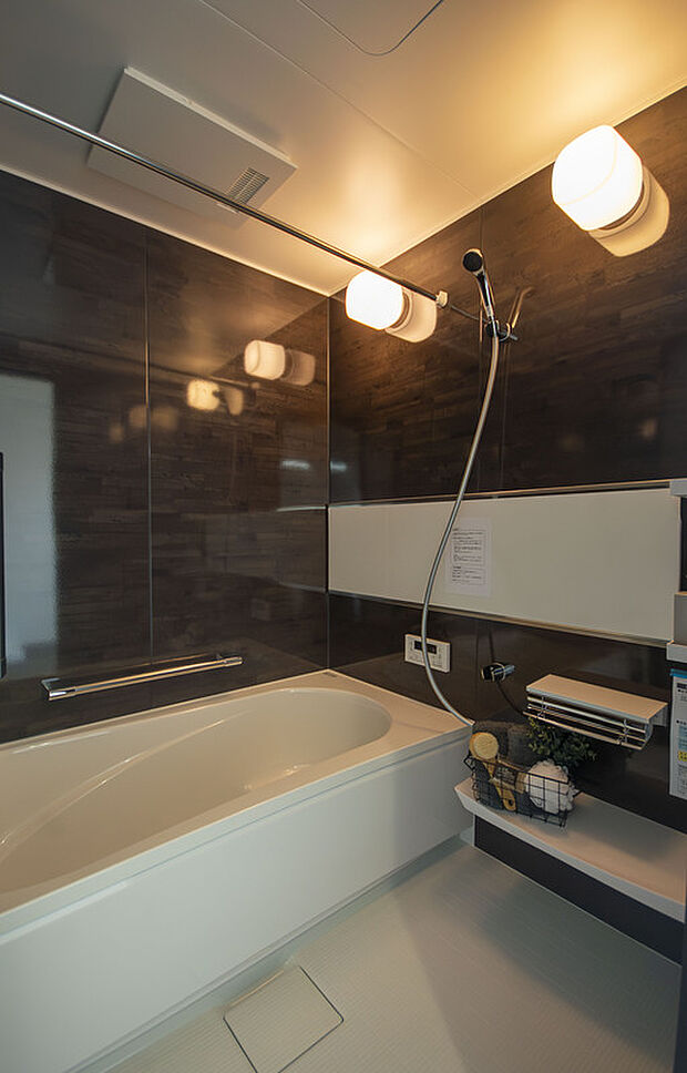 【【浴室】】ダークブラウンのパネルを採用した、温かみのある雰囲気の浴室です。浴槽に浸かりながらでも使用できる横長のワイドミラーを設置。浴室乾燥機も備わっています。