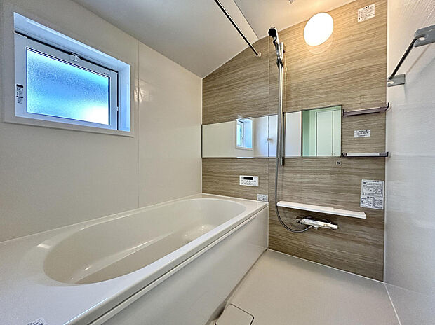 【【浴室（1号棟）/※同仕様参考】】親しみやすい、明るい木目調のアクセントパネルを施したバスルーム。シャンプーなどを置くのに便利な、2段のワイドシェルフを設置しています。