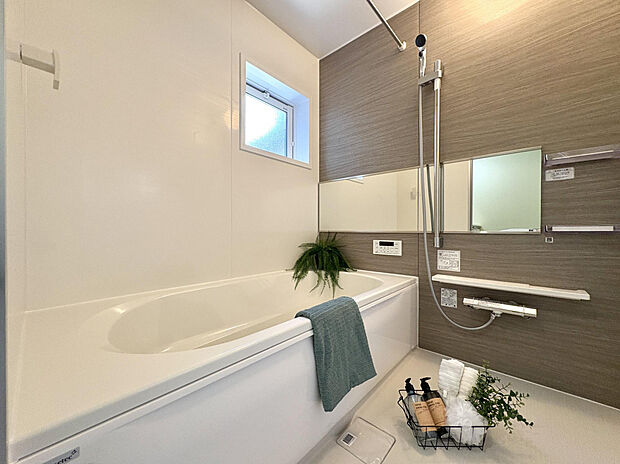 【【1号棟/浴室（家具付き販売ではございません。）】】ブラウンのアクセントパネルを採用した、温かみのある雰囲気の浴室。横長のワイドミラーで、より広さも感じられます。天候や時間に関わらず洗濯物を乾かせられる、浴室乾燥機が備わっています。