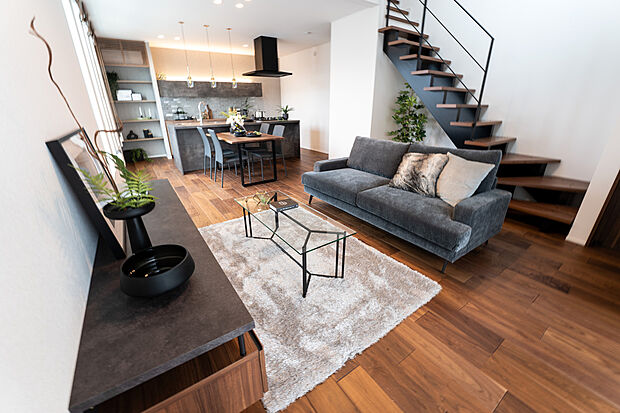 【1階約20帖LDK/C号地モデルハウス】フロアは無垢材の豊かな表情や質感の美しさが楽しめる挽き板フローリングに。オープン階段のささら桁や手擦りはブラックを採用し、空間全体を引き締めます。