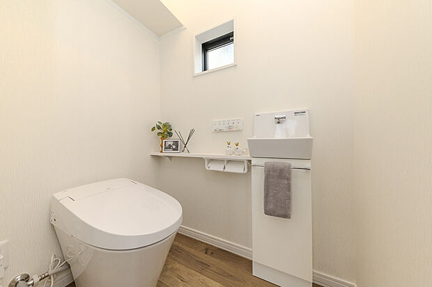 【【1号地/トイレ】】各階に温水洗浄便座付きのトイレを配置しました。こちらは1階のトイレです。トイレ内に手洗い水栓を設置しているので衛生的。玄関に隣接し、帰宅後の手洗い場としてもご活用いただけます。スマートフォンや本を置くのにちょうどいいカウンター付き◎