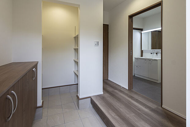 【1階玄関/A号地】土間収納を備えたエントランス。ロータイプの玄関収納にグリーンなどを飾って彩りを添えることもできます。泥んこのお子さまが帰宅しても、洗面脱衣室や浴室へ直行できる機能的な動線です。