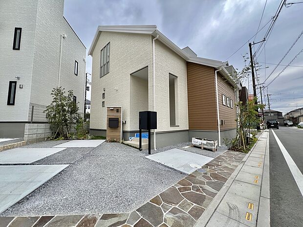 【【100号棟外観】】ベージュとブラウンの落ち着きのある外観です。インターホン付の機能門柱と宅配ボックスを採用。LDKはゆとりのある約20帖。対面式キッチン・リビング階段を採用した、コミュニケーションを育める空間設計です。