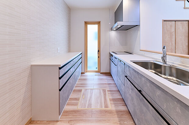 【【キッチン/3号棟】】対面式キッチンは料理や片づけをしながら家族との会話も弾みます。背面にはデザインを統一したカップボードがあり、調理器具や食器ストックがすっきりと収納可能です。