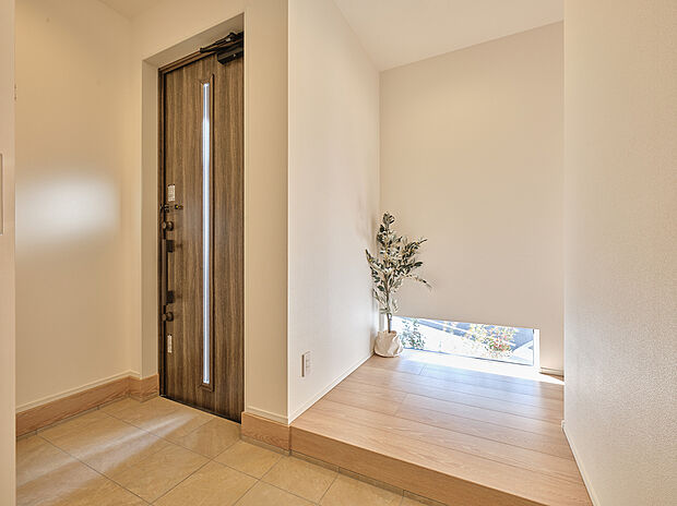 【玄関ホール】靴や上着などを収納できるSICを配置した広々玄関。ホールの地窓からはやさしい光が入り、時間帯によって異なる植栽の影が空間を演出します。