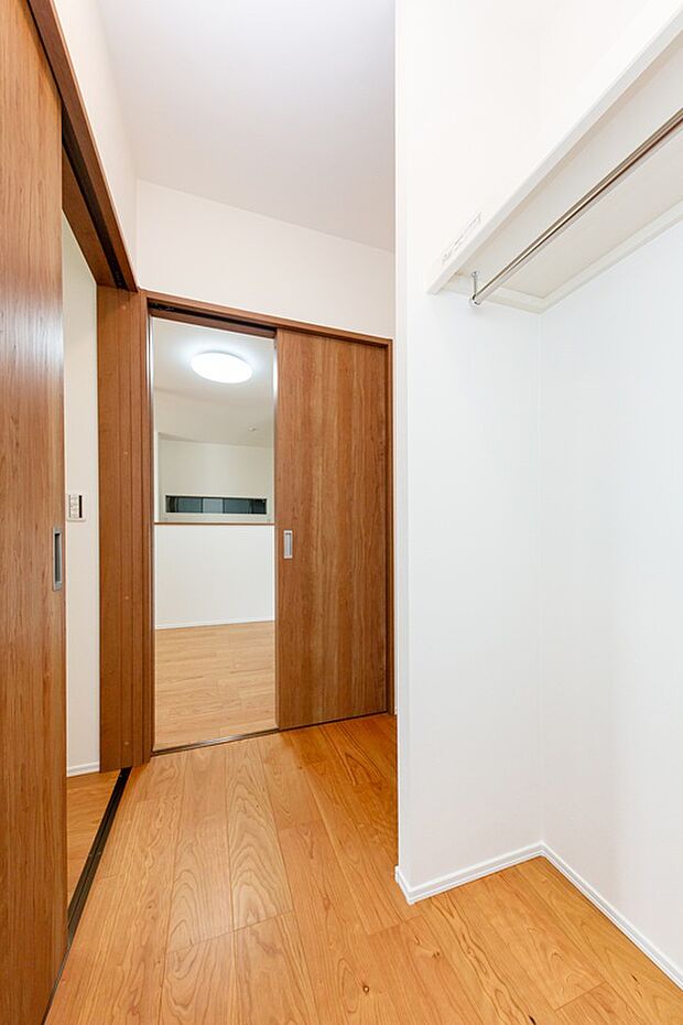 【【ファミリークローゼット/13号地モデルハウス】】1階に大容量のファミリークローゼットを設置。ファッションアイテムなどを収納可能。廊下とリビングから出入りできる2WAY仕様です。/2024年1月撮影