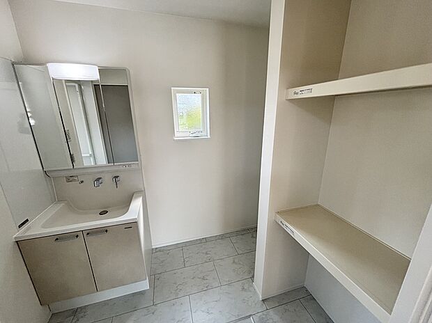 【【洗面脱衣室(12号地モデルハウス)】】身支度がはかどる、3面鏡付きの洗面化粧台を採用。タオルやパジャマの収納にも便利な、オープンタイプの棚がございます。/2025年4月撮影