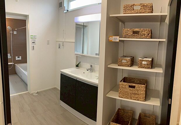 【リネン収納つき洗面脱衣室】タオルや下着類、洗面用品を収納できる可動棚付きの収納スペース。おしゃれなカゴに洗面用品を収納すれば、生活感の出やすい水回りがキレイに片付きます。室内干しが出来るので、雨の日のお洗濯も安心です。