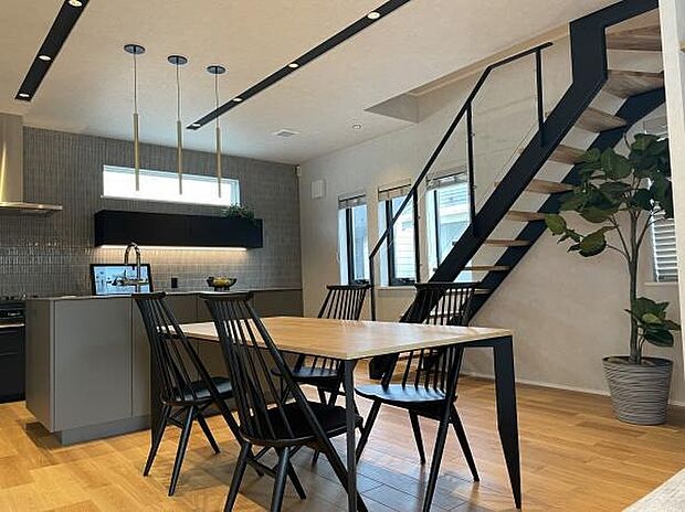 キッチンとダイニングがつながり、料理中も家族との会話が弾む空間。木の温もりに黒のアクセントが映え、視線が抜ける階段が開放感を添えます。