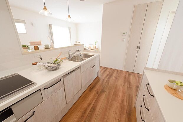 【1階キッチン/B号地モデルハウス】ホワイトを基調とし、木目のポップアップ天井がオシャレ。パントリーやカップボードにより収納力も◎背面にリビング階段を設け、コミュニケーションが自然と育まれます。