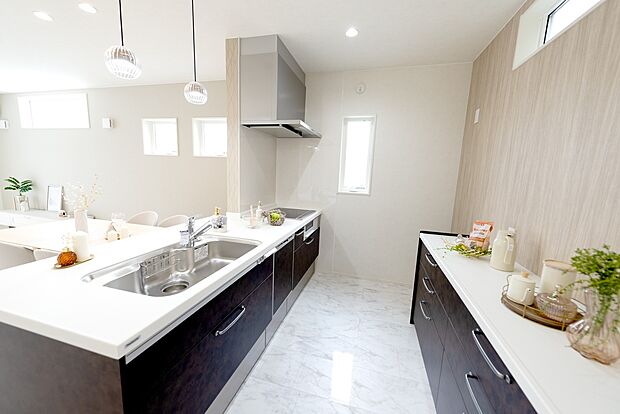 【【1階キッチン/B号地モデルハウス】】ホワイトのワークトップとダークカラーの扉の対比が美しいシステムキッチン。食器洗浄乾燥機付きです。キッチン背面にはデザインを揃えたカップボードがあり、ゆとりあるスペースに。お料理が楽しくなりそうです。