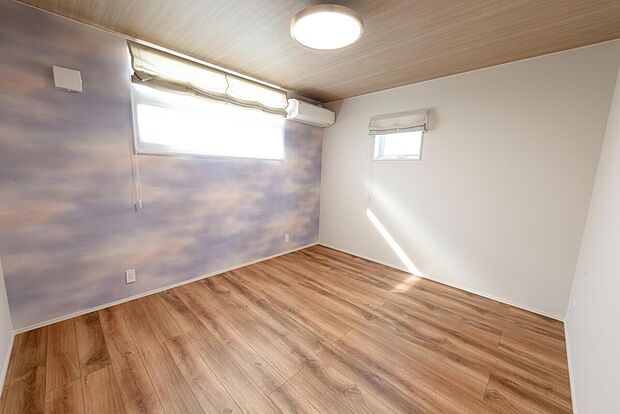 【【2階約7.8帖洋室/B号地モデルハウス】】フロアとトーンをあわせた木目天井×様々な空模様を想い起こすアクセントクロスが印象的な洋室です。子育て中のご家庭など、ご家族揃ってお休みいただくこともでき、主寝室としてのご利用もおススメです。