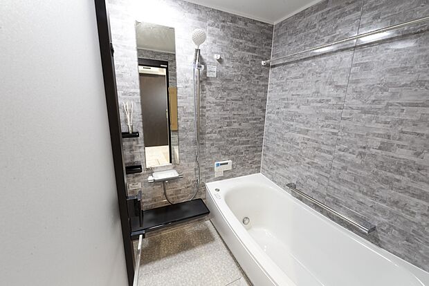 【【1階浴室/B号地モデルハウス】】浴槽横の壁に手すりがあり、安心して出入りすることができます。浴室乾燥機とハンガーパイプを備えており、雨の日や花粉の季節の室内干しにも便利です。