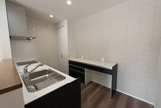 【【1階キッチン/A号地モデルハウス】】シンク前の壁は少し高さを出し、コンロ前にはしっかりと壁を設けることで、ダイニングへの水撥ねや油跳ねを防ぎます。対面キッチン背面にカップボードやパントリーを横並びで配置し、調理器具などの保管に便利です。