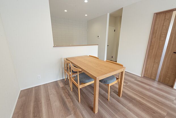 【【1階LDK約17.8帖/A号地モデルハウス】】キッチン前にダイニングテーブルを配置すると、お料理の配膳やお片付けがスムーズ。キッチン横の扉からつながる水回りは、洗面室と脱衣室をセパレート。ご家族が入浴中でも洗面室をご利用いただけます。