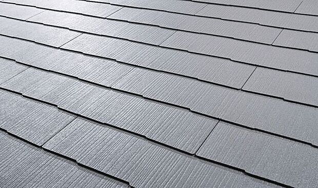 【屋根材「カラーベストコロニアルクァッド」】外観に馴染む横一文字葺きデザイン。重量は一般的な陶器瓦の1／2以下。建物全体の重心を低く抑えられ耐震性に優れます。トップコートは耐候性アクリルコート、その下に「2つの無機層」を設け色感をキープします。