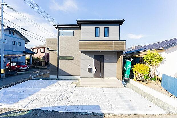 【モダンなキューブ型外観】 グレーを基調としたスタイリッシュな佇まい。青空に映える洗練されたデザインです。前面道路との高低差が少なく、毎日の車の出し入れやベビーカーでの移動もスムーズです。