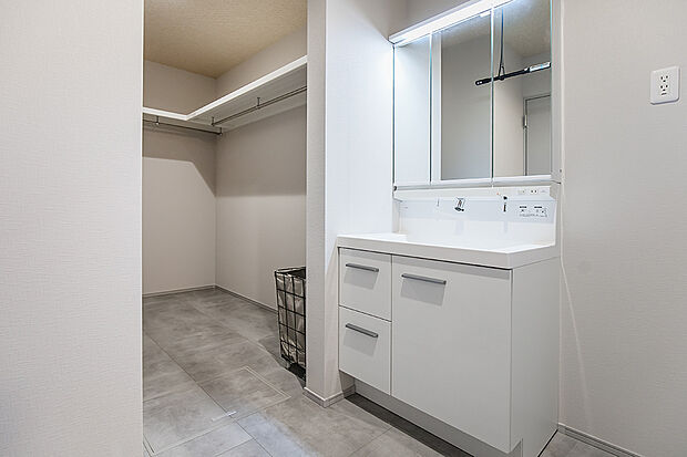 【洗面室｜室内物干しでちょっと乾かすのにちょうど良い◎】三面鏡タイプの洗面台を備えた上質な洗面空間。すぐ隣にはウォークインクローゼットを配置し、身支度や収納の動線もスマートに。/2号地