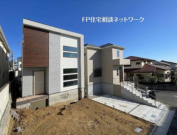 【外観】 洗練された都会的な外観デザイン。木目調のアクセントウォールが温かみを添え、モダンな印象を与えます。広い前面スペースは、将来の夢が広がる駐車スペースやガーデニングに最適です。