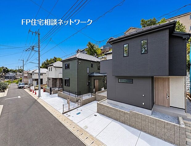 【現地写真】  新築住宅が並び、統一感のある街並み。青空の下、モダンな外観デザインが際立ちます。周囲の自然も感じられ、落ち着いた暮らしを実現します。
