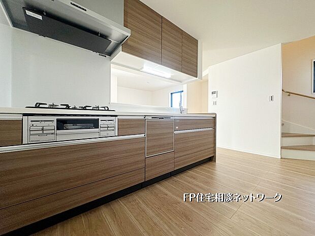 【キッチン】木目調のデザインが温かみを添えるシステムキッチン。広い作業スペースと充実した収納で、毎日の料理がもっと快適に。リビングとつながる開放的なレイアウトも魅力です。