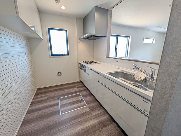 【キッチン】明るく清潔感のあるキッチン。白を基調としたデザインと木目調の床が調和し、開放的で作業しやすい空間を演出しています。