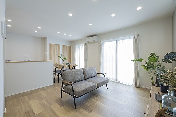 【【1階約15.87帖LDK/2号地モデルハウス】】大きな窓からたっぷりの陽光が注ぎ、ダウンライトがノイズレスで広がりを生む団らんスペース。窓の外にはガーデンの伸びやかな景観が広がり、季節の花を眺めたり、水遊びを楽しむお子様をリビングから見守ることも。