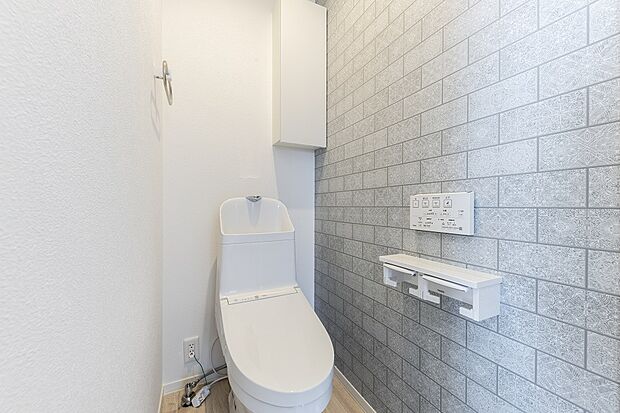 【2階トイレ】デザイン的なアクセントクロスを採用した2階トイレ。収納も備え付けです(2024年3月撮影)