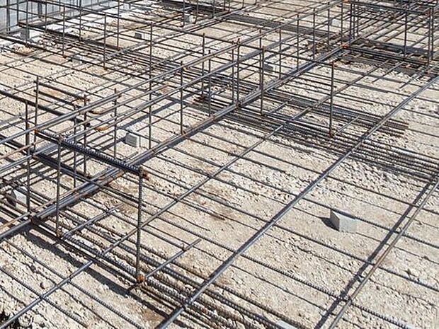 【剛性・耐久性にすぐれた「ベタ基礎」】コンクリートで建物の下一面を支える工法。　基礎鉄筋を張り、強度を高めたベタ基礎の耐圧盤を1階の床下全面に施工し、広い耐圧盤の面で建物の荷重を地盤に伝えます。