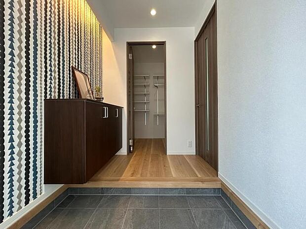 【玄関【2号地】（2025年8月撮影）】玄関はアクセントクロスと間接照明で来客をおもてなし