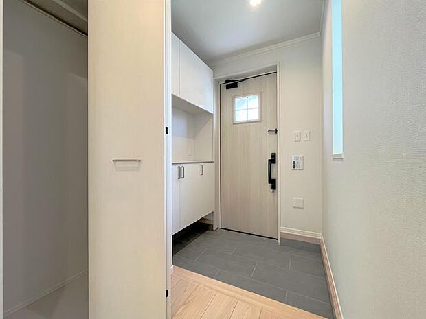 【A棟玄関（2023年5月撮）】白を基調とした清潔感のある玄関　玄関内には衣服収納スペースを設置しました
