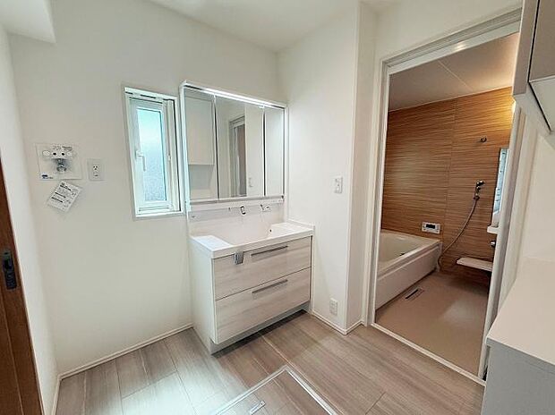 【A棟洗面脱衣室】洗面台背面にも収納付き。機能的で清潔感あふれるバスルーム。（2025年7月撮影）