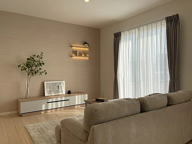 やわらかな陽ざしが差し込むリビングは、ナチュラルな色合いでまとめた落ち着く空間。アクセントクロスや間接照明がやさしい奥行きを演出し、家族でゆったりくつろげる温かな雰囲気が魅力です。