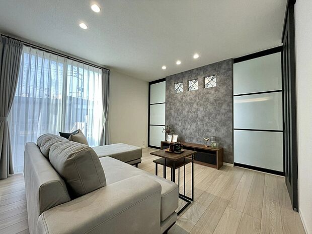 【リビング】シックなアクセントクロスが空間を引き締め、落ち着いた雰囲気に。大きな窓からやわらかな光が広がり、心地よくくつろげる空間です。毎日のリラックスタイムを少し贅沢に楽しめます。