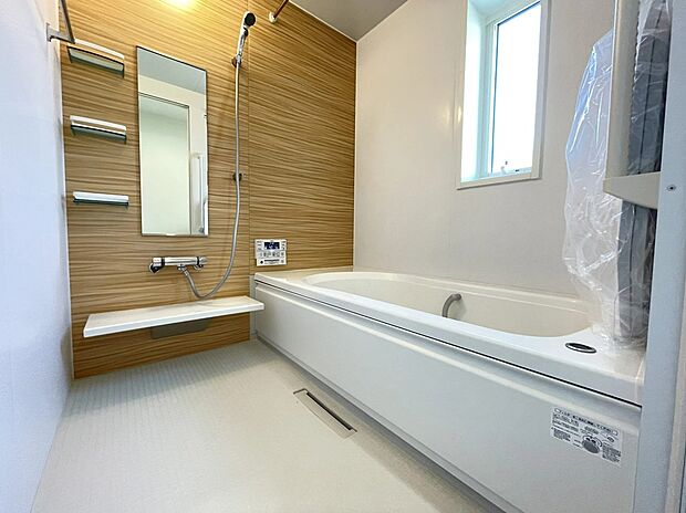 【浴室】木目調のアクセントパネルが温かみを添える、1坪タイプの広々としたバスルーム。ゆったりとした浴槽で1日の疲れをリセットできます。小窓からは自然光も入り、明るく清潔感あふれるリラックス空間を叶えました。