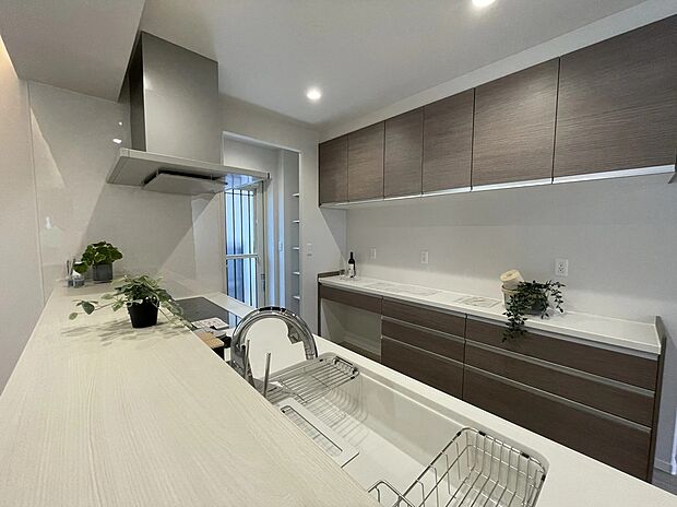 【キッチン】明るいホワイトの天板と、重厚感のある木目柄カップボードを組み合わせたセパレートキッチン。間接照明の演出が、奥行きと上質な空間を創り出しています。