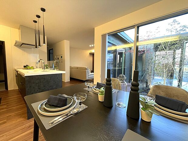 【キッチン・ダイニング】大きな窓から光と緑を取り込むダイニング空間。キッチンと緩やかにつながり、開放感と心地よさを感じながら食事を楽しめます。