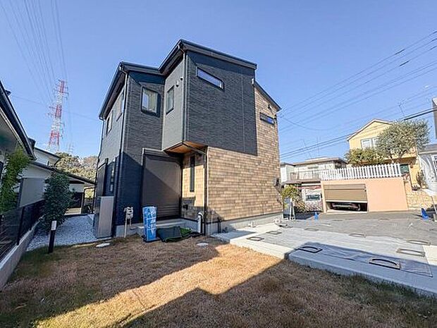 ダークグレーと木目調のコントラストが美しい、モダンな外観の住まいです。広々とした庭と駐車スペースは、お子様の遊び場や家族のアウトドアリビングとしても活躍します。