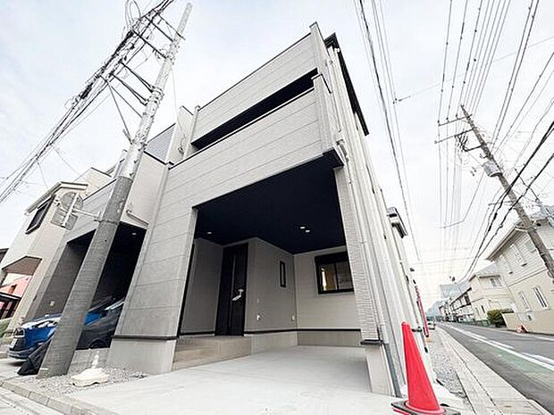 【現地外観写真】1号棟。重厚感のあるデザインが目を引くファサード。ビルトインガレージ一体のポーチが、雨の日のお出かけをサポート。