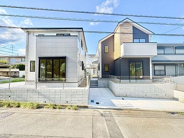 青空の下、モダンなデザインが目を引く2棟の住まい。明るい日差しが差し込む空間で、家族の絆を育む毎日を。