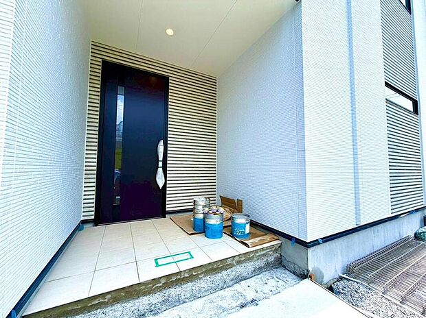 【玄関】モダンな黒い玄関ドアと清潔感のある白い壁が、ご家族を温かく迎えます。明るいポーチは、毎日の外出・帰宅を心地よく演出するでしょう。