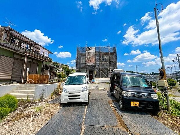 【前面道路含む現地写真】青空が広がる開放的なロケーションに、ご家族の未来を築く新しい住まいが建設中。ゆとりの駐車場で、カーライフも快適です。
