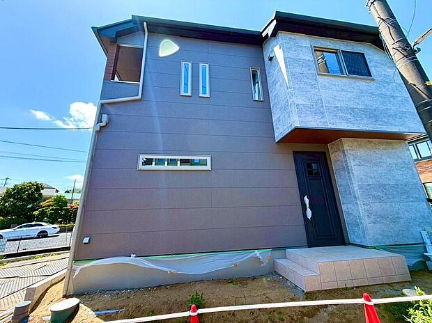 【現地外観写真】青空に映える、モダンで洗練された外観の住まい。グレーと石目調のコントラストが美しいデザインが、ご家族の毎日を鮮やかに彩ります。