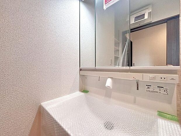 【洗面台・洗面所】目線に合わせた三面鏡付洗面化粧台を採用しました。三面鏡の裏側には収納棚を確保。スキンケア用品やヘアケア用品などをすっきり整理できます。また収納棚を多く設けており、脱衣スペースを広く確保しております。