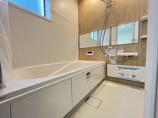 【浴室　B号棟現地写真】■リクシル　システムバスルーム「AX」。フロアはスポンジが奥まで入り掃除がラクラク。また独自の断熱層を使用しているため冬場でも冷やっとしません。