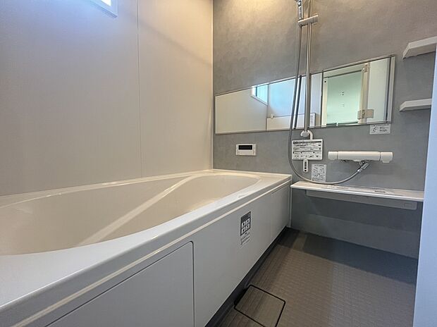【浴室　A号棟現地写真】■リクシル　システムバスルーム「AX」。フロアはスポンジが奥まで入り掃除がラクラク。また独自の断熱層を使用しているため冬場でも冷やっとしません。